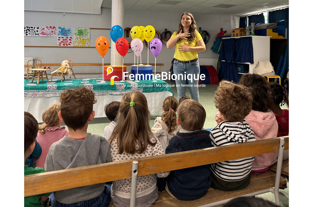 Clara signe "heureux" lors du spectacle sur les emotions appelé "Signe-moi une histoire !" auprès des enfants en école primaire.